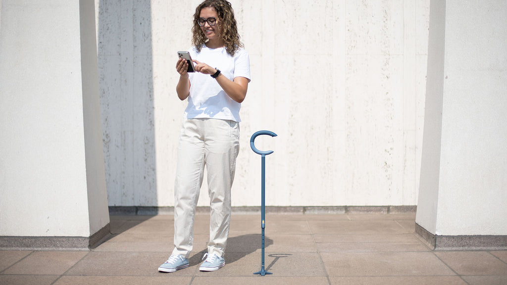 woman standing next to c-grip cane holding phone