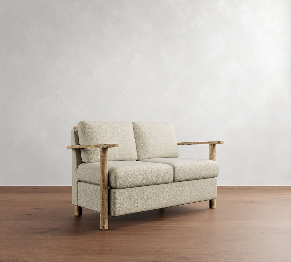 Beige sofa with wooden armrests on a wooden floor against a white wall