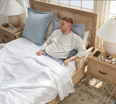 man in a bed with his arm on the bed frame