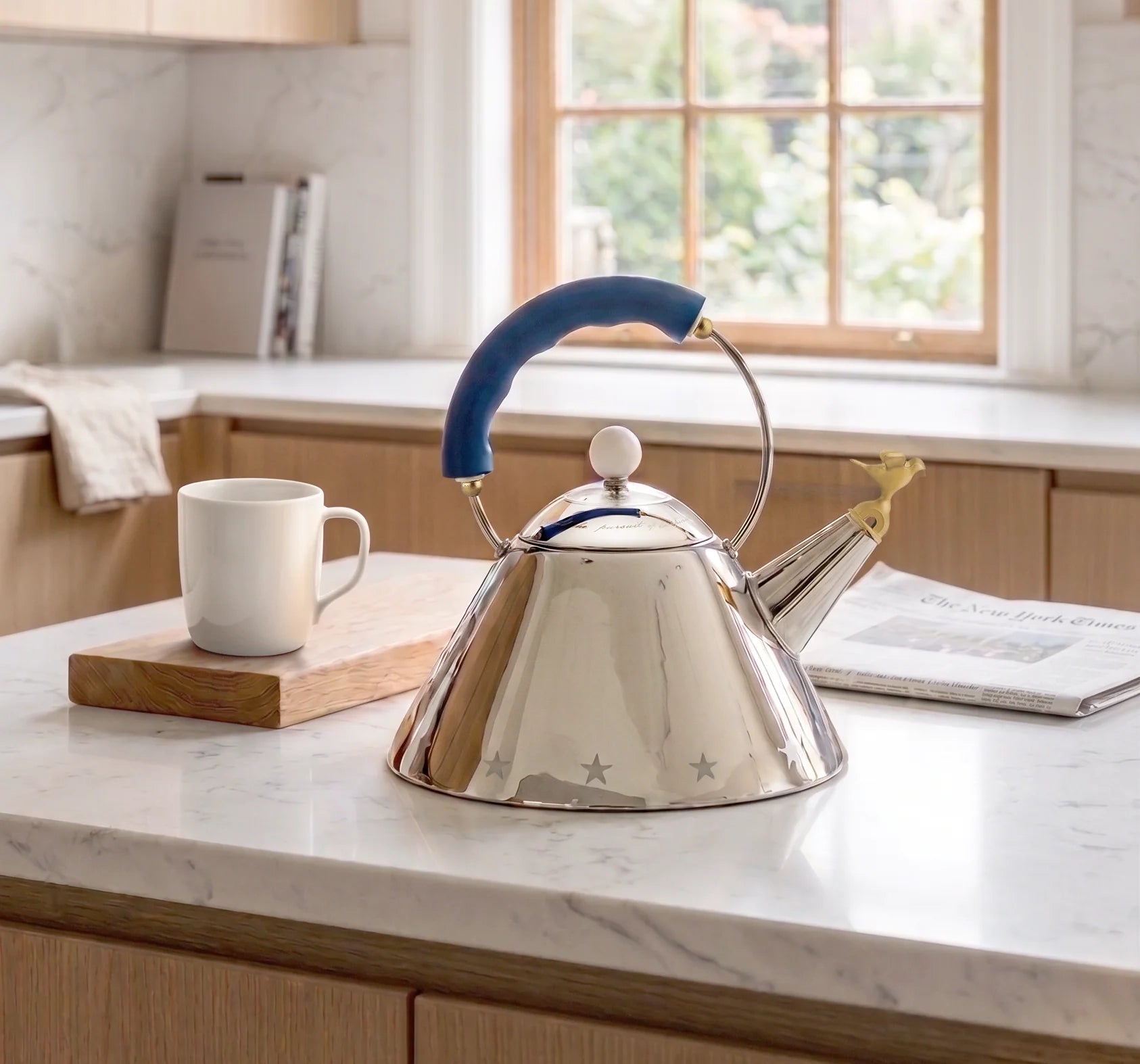 Stainless steel kettle with blue handle on a kitchen counter