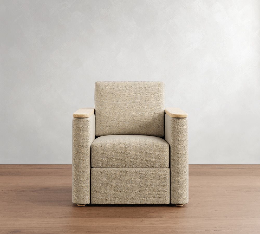 Beige armchair with wooden armrests on a wooden floor against a white wall