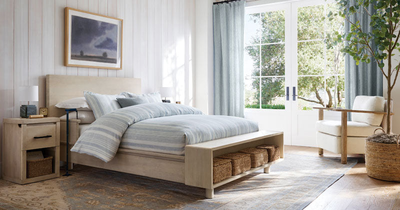Cayman bed with baskets, side table, chair,  big window doors, and picture frame