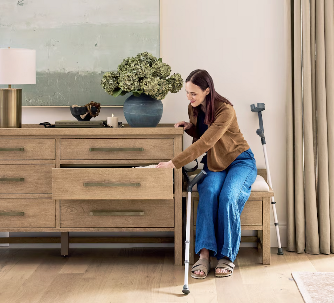 woman sitting on bench putting clothes in dresser