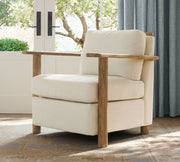 Beige armchair with wooden arms and legs in a room with curtains and a window.