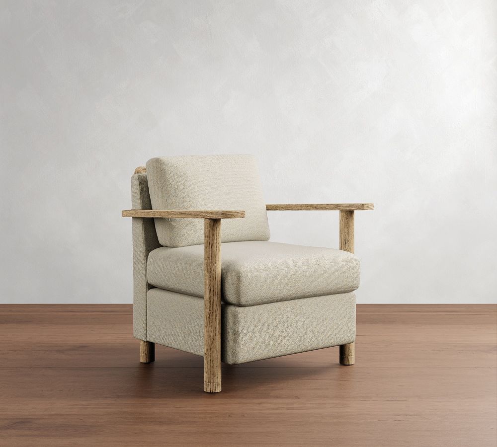 Beige armchair with wooden arms and legs on a wooden floor against a white wall