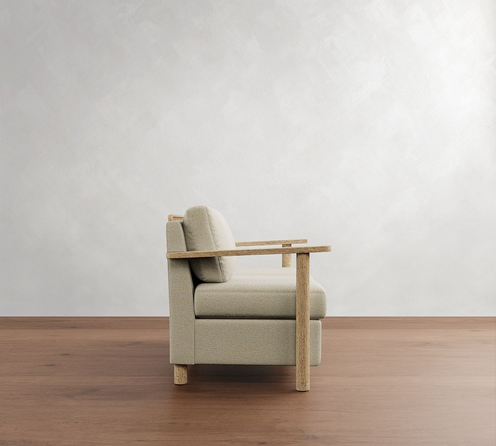 Beige armchair with wooden legs on a wooden floor against a white wall