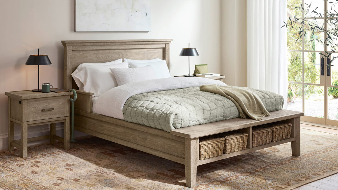 Bed with Baskets in footer perch with nightstand to left with a coffee mug, lamp, and c-grip cane