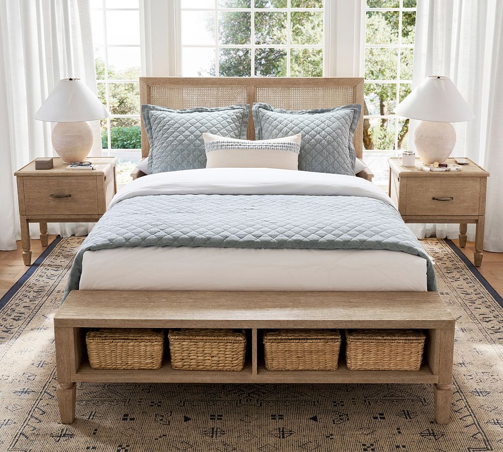 Bedroom with wooden bed, bench, and nightstands with lamps.