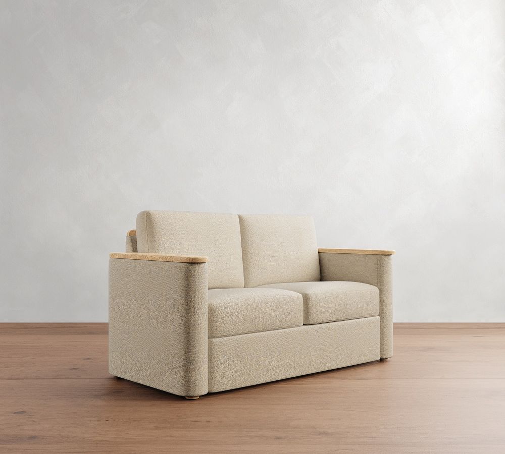 Beige sofa with wooden armrests on a wooden floor against a white wall