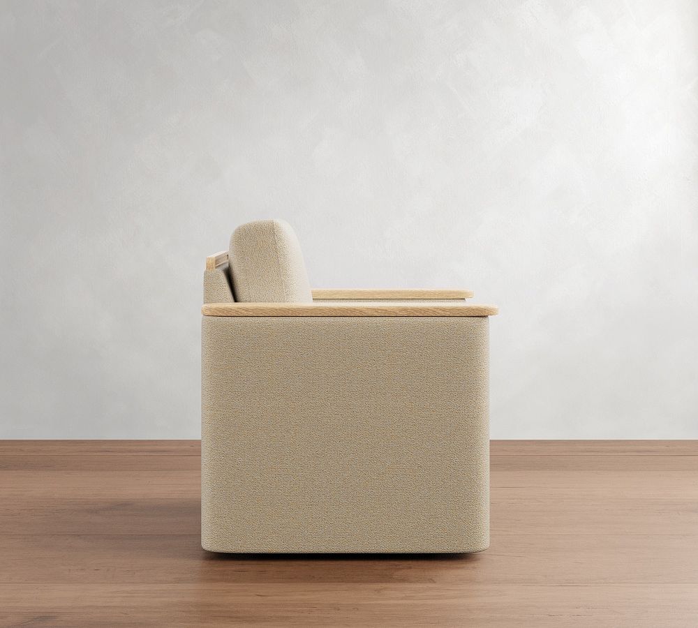 Beige upholstered chair with wooden armrests on a wooden floor against a white wall