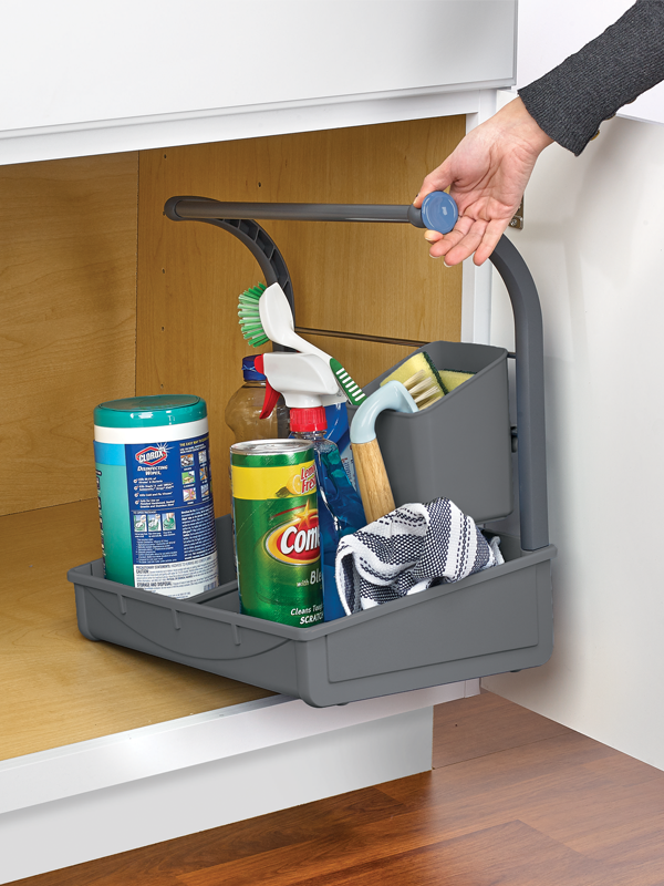 A gray under sink storage caddy with various cleaning supplies placed on its shelves and dividers, is shown partially extended from a cabinet.
