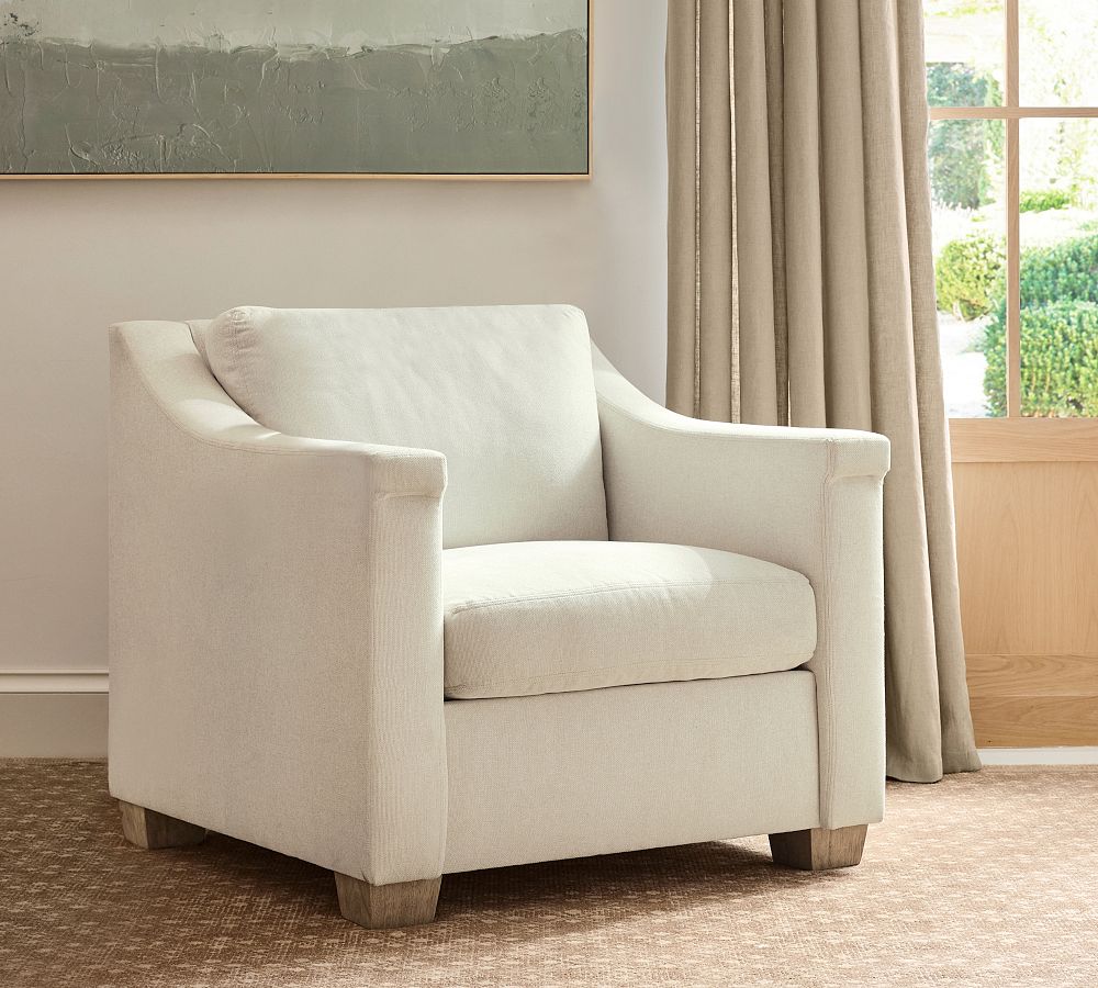 Beige armchair in a room with a painting and curtains