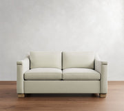 Beige sofa on a wooden floor with a white wall background